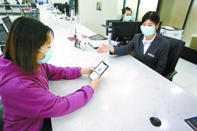  在東城區(qū)政務(wù)服務(wù)大廳，前來辦事的企業(yè)工作人員通過“北京通”授權(quán)電子證照應(yīng)用